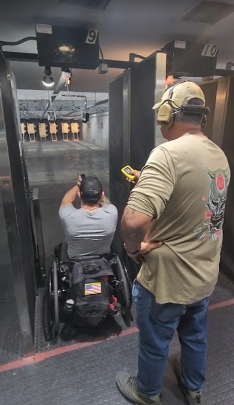 Gideon Training Solutions instructor coaching a student in a wheelchair at an indoor shooting range, demonstrating inclusive and adaptive firearms training in DFW. Instructor provides hands-on guidance as student engages targets at lanes 9 and 10.